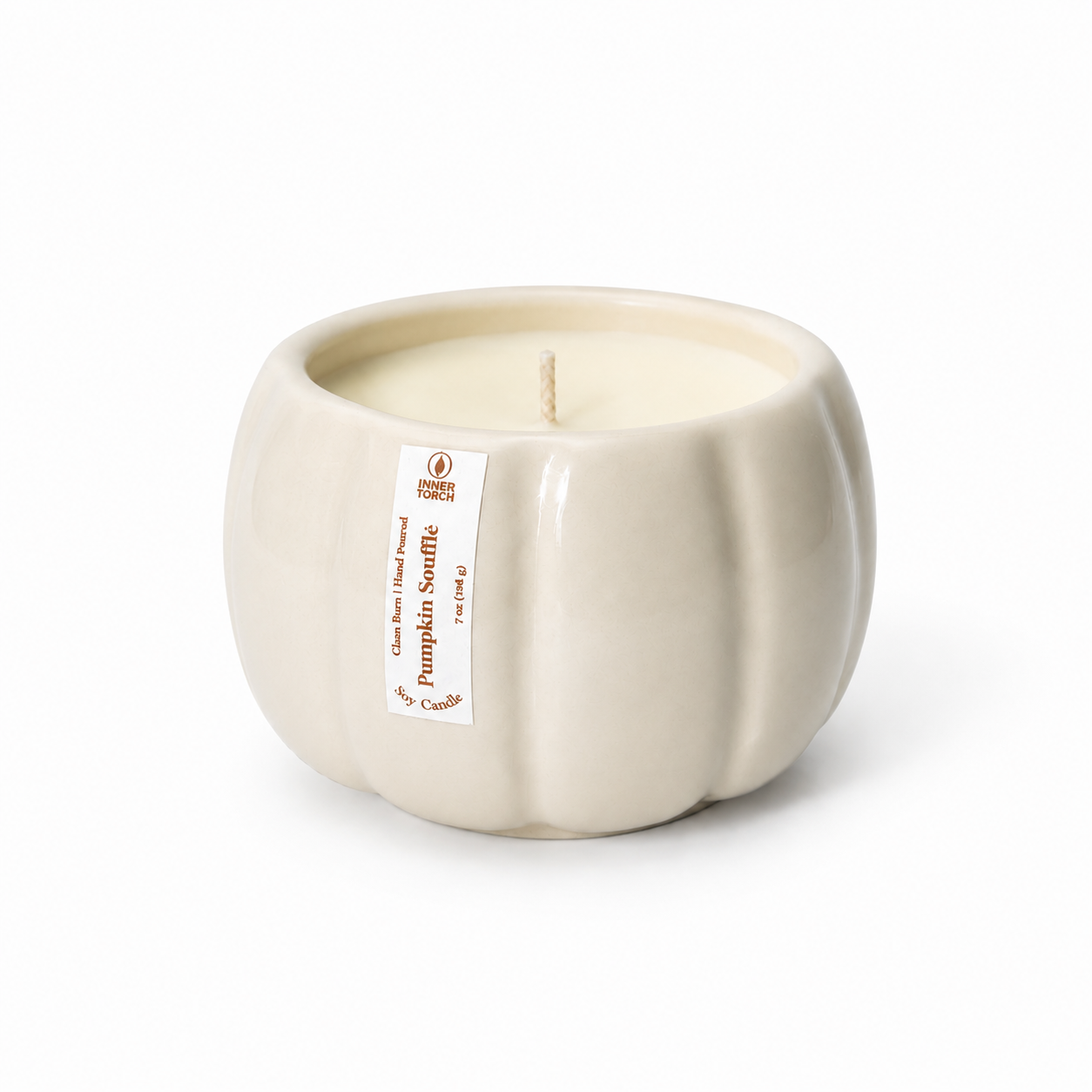 A pumpkin-shaped ceramic candle in an off-white cream color with a white paper label on the side, set against a plain white background.